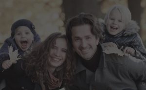 A young family with two kids who are happy and excited in their fall coats.